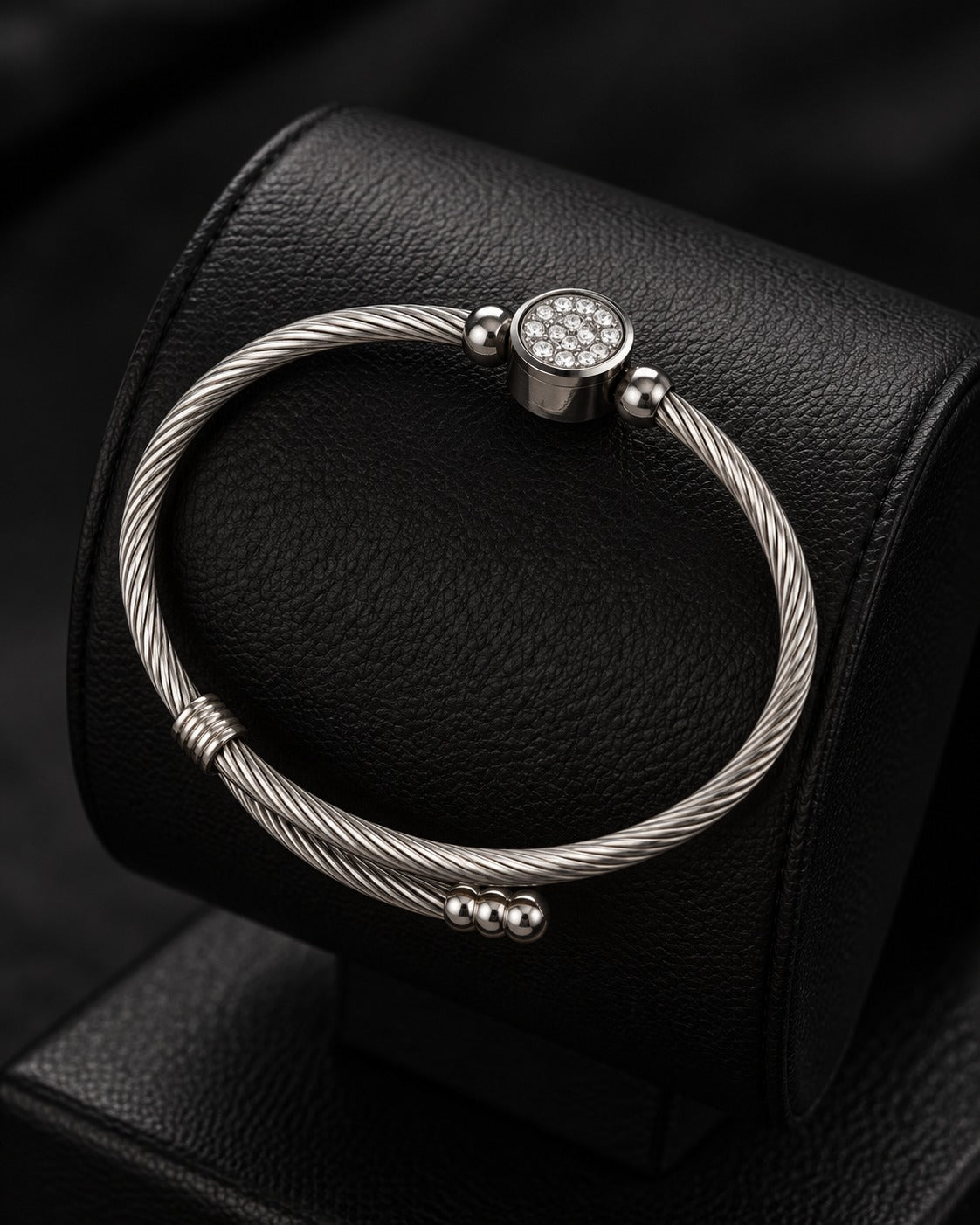 Silver-tone twisted cable bracelet with sparkling clasp detail on an olive display