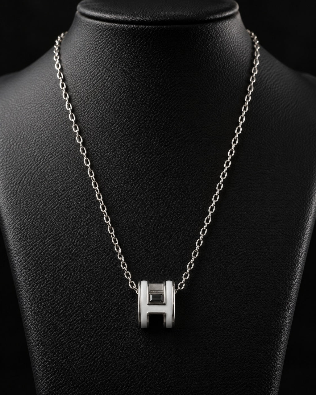Silver-tone H-link pendant necklace styled on a dark display