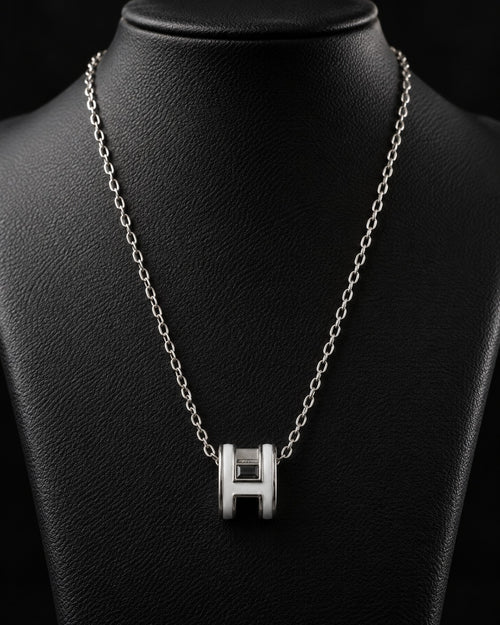 Silver-tone H-link pendant necklace styled on a dark display